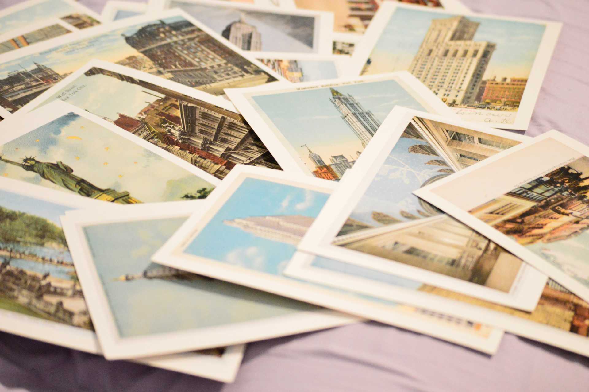 A pile of postcards that one would get while on vacation scattered and piled on a surface