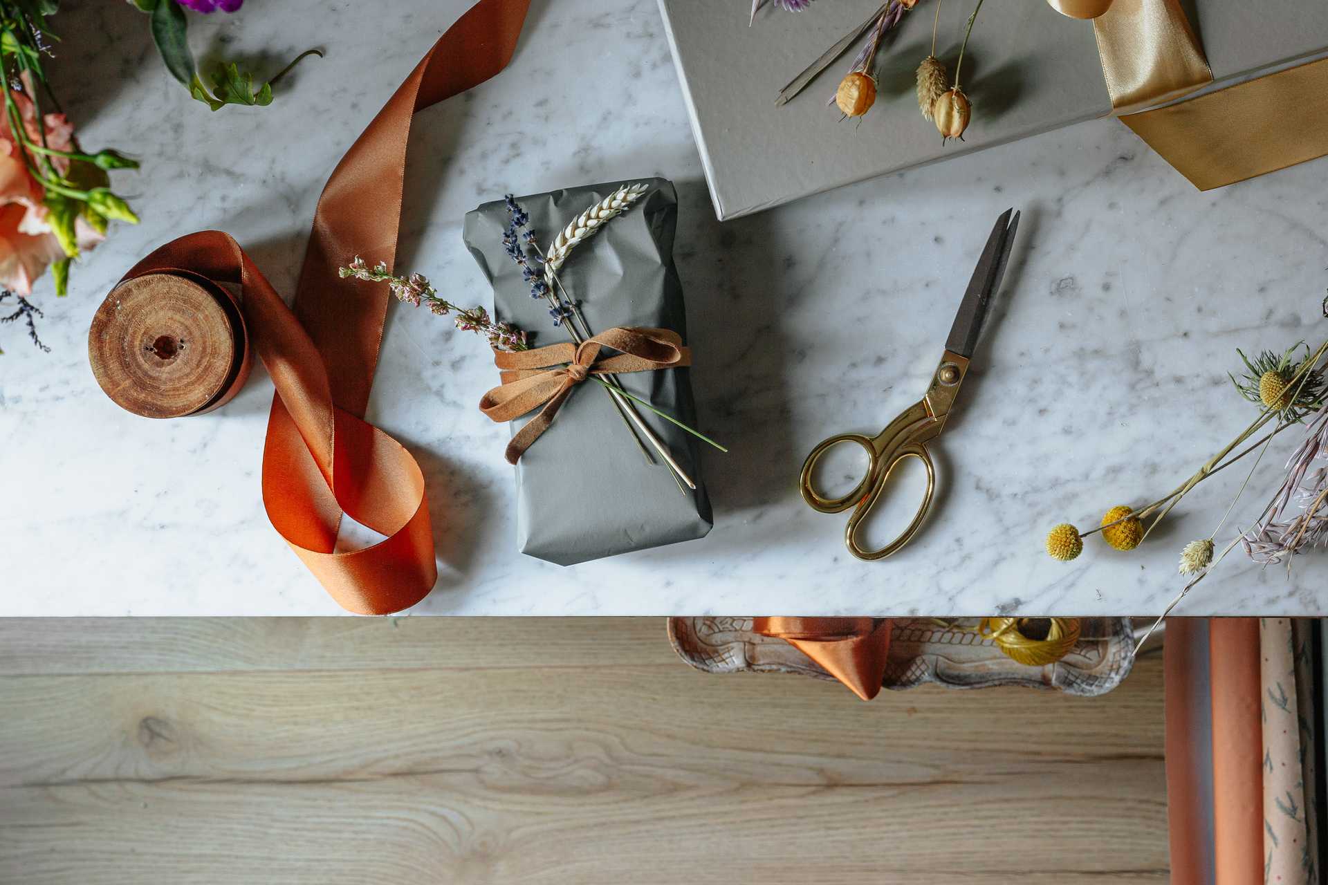 A wrapped package with ribbon, scissors, and decorative plants nearby