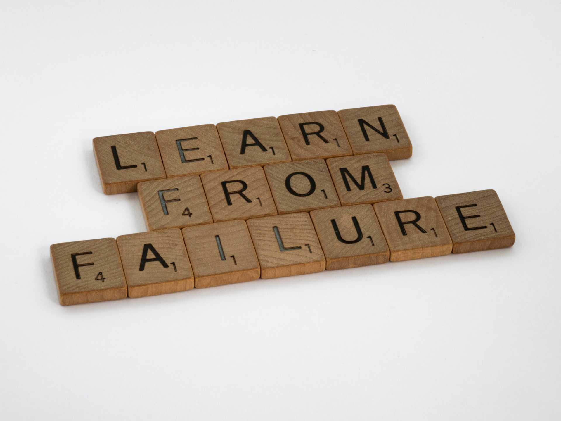 Wooden scrabble tiles spelling out LEARN FROM FAILURE with one word stacked the other