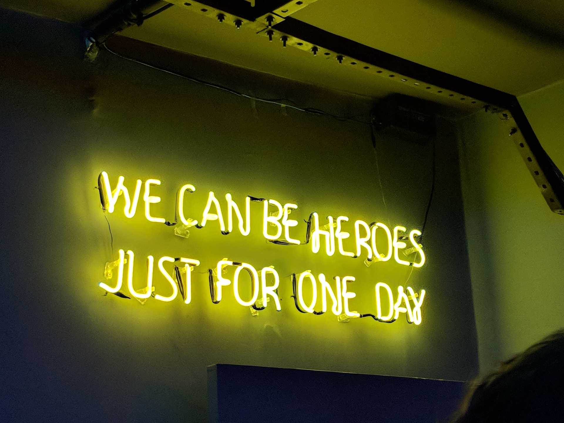 A neon sign that reads WE CAN BE HEROES JUST FOR ONE DAY