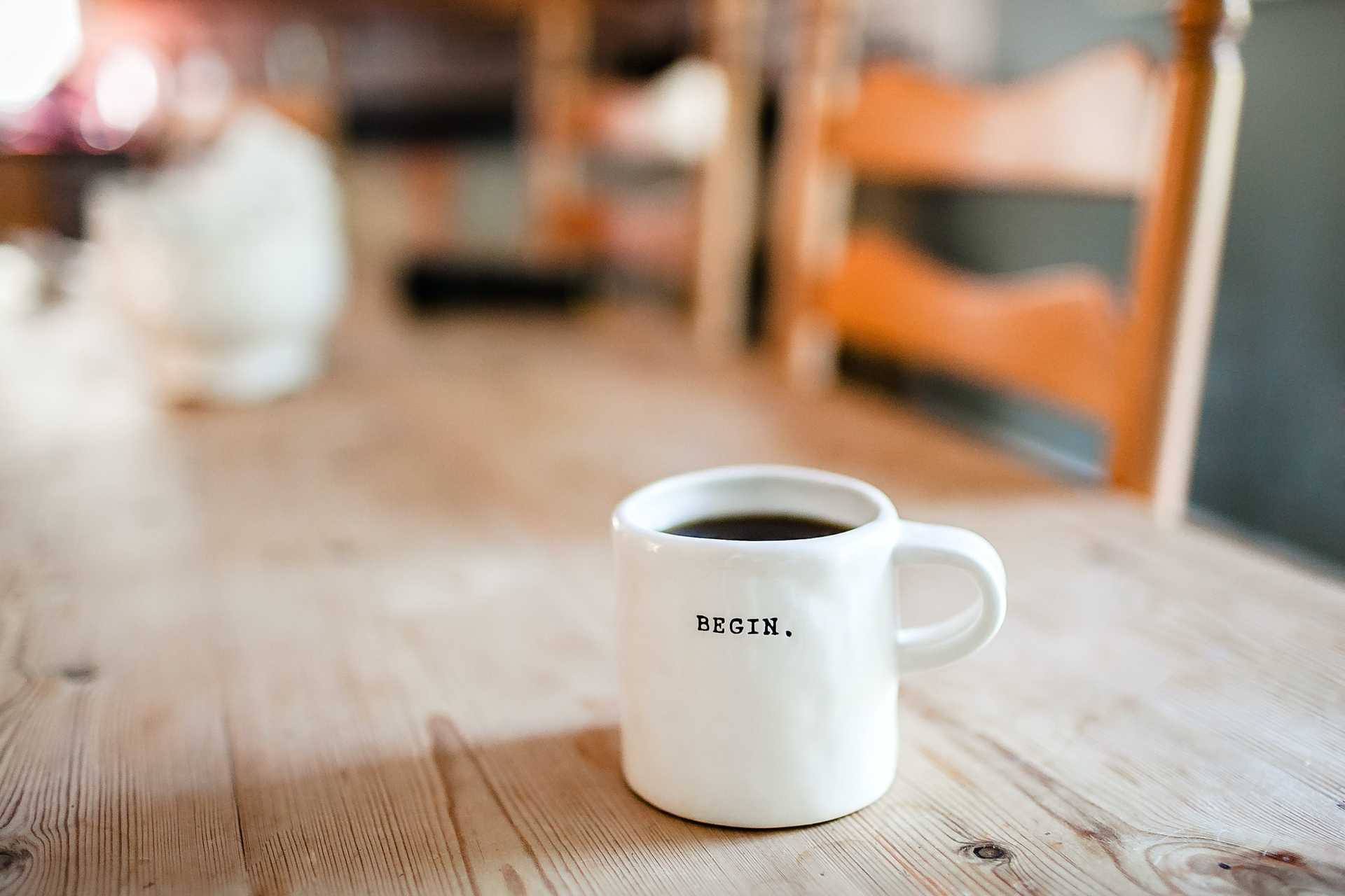 A mug on a table that reads BEGIN.